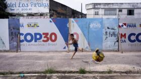 A boy kicks a football near a COP30 sign in Belem, Brazil, on March 23, 2025.