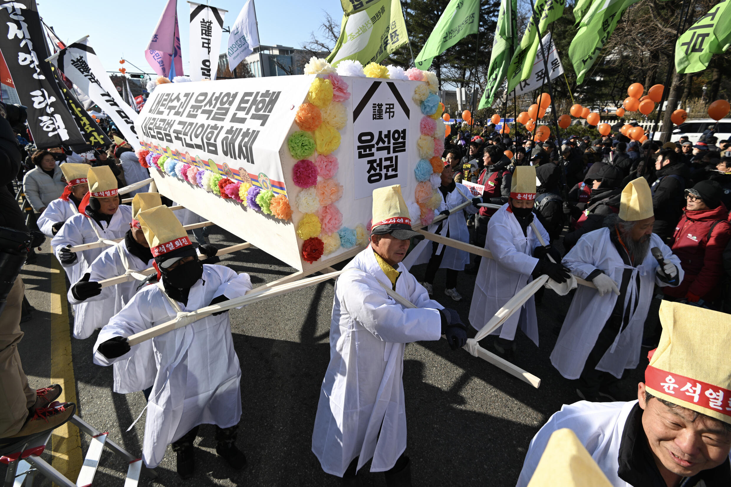 Des manifestants portent un cercueil symbolisant le président Yoon Suk Yeol, le 14 décembre 2024 devant le Parlement à Séoul
