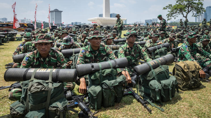 Indonesian soldiers wait for orders in Jakarta as hundreds protested outside parliament.
