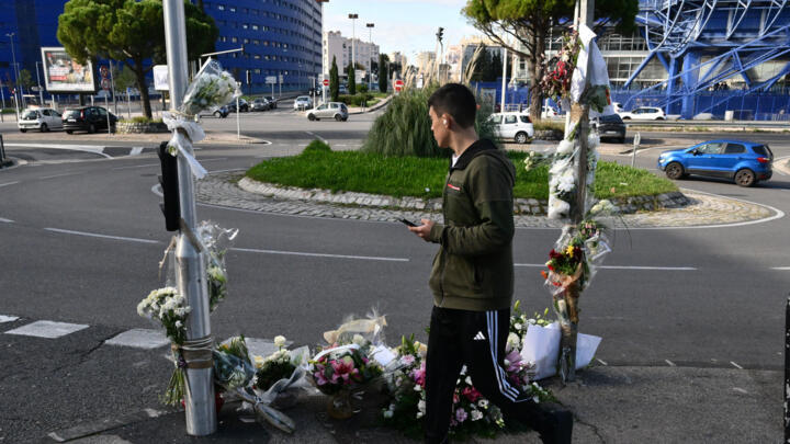A pedestrian walks past bouquet of flowers at a makeshift memorial where Mehdi Kessaci was murdered, the day of his funeral in Marseille on 18 November 2025.