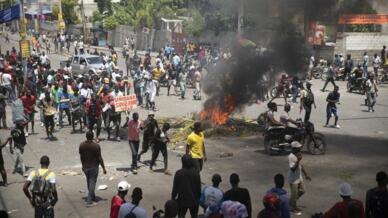Decenas de personas alrededor de llantas quemadas por grupos de manifestantes durante una protesta para exigir mejores condiciones de vida y la renuncia del primer ministro haitiano, Ariel Henry. En Puerto Príncipe, Haití, el 7 de septiembre de 2022