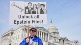 Man holds a sign before a news conference on the Epstein files in front of the Capitol on November 18, 2025, in Washington.