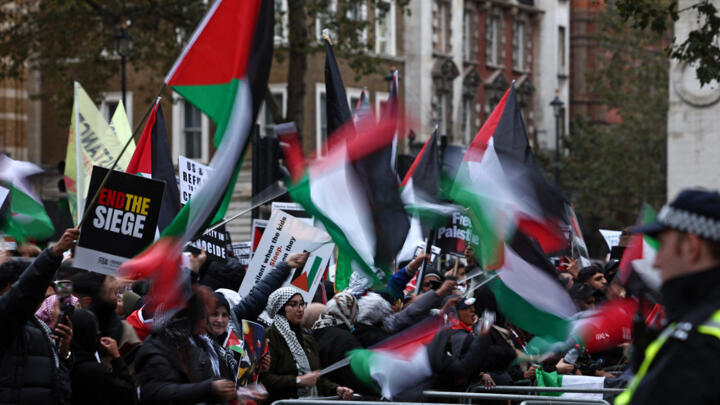 Protesters hold up placards and Palestinian flags outside Downing Street after taking part in the ‘March for Palestine’ in London on October 28, 2023.