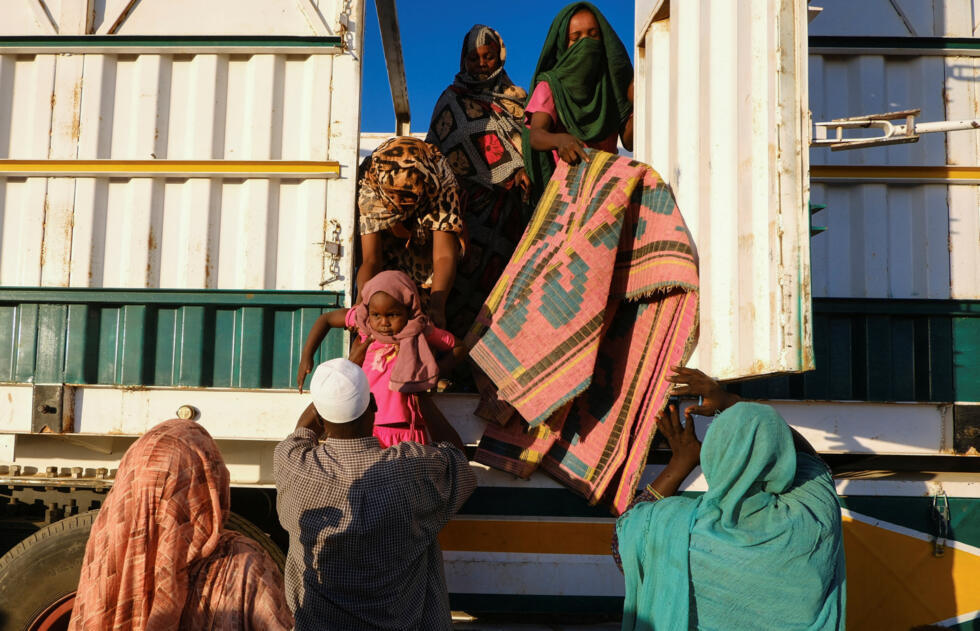 Una mujer desplazada de Al-Fashir entrega a un niño a un voluntario para que les ayude a bajar de un camión, en un campamento de desplazados en Al-Dabba, Sudán, el 19 de noviembre de 2025.