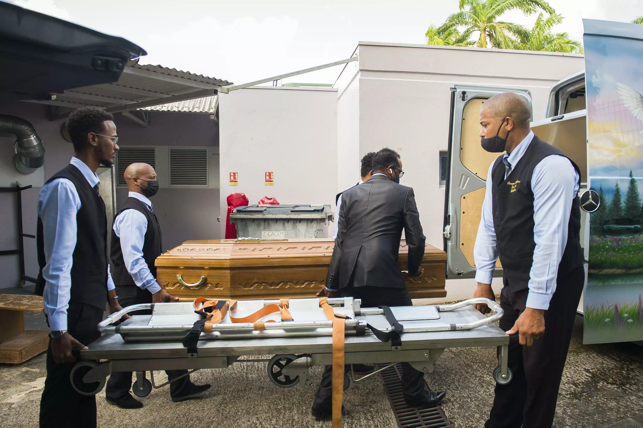Des employés des pompes funèbres chargent dans un corbillard le cercueil d'une personne décédée du Covid-19, le 17 août 2021 à Fort-de-France, en Martinique