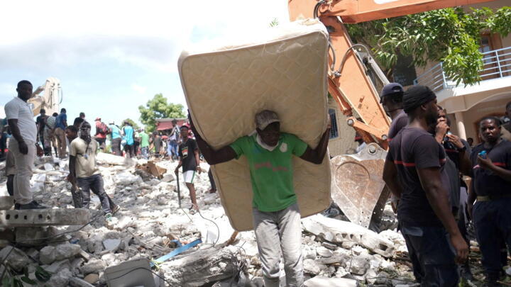 A resident carrying a mattress at the site of a collapsed hotel aftet Haiti's earthquake. 