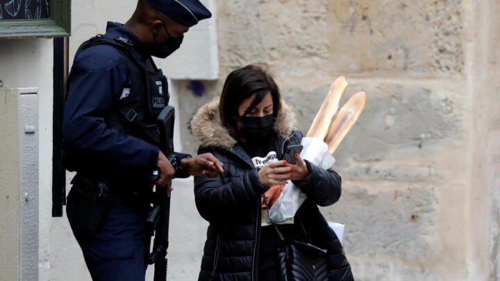 A policeman checks the authorisation documents of a woman on a street in Paris on the first day of the second national Covid-19 lockdown in France on October 30, 2020. 