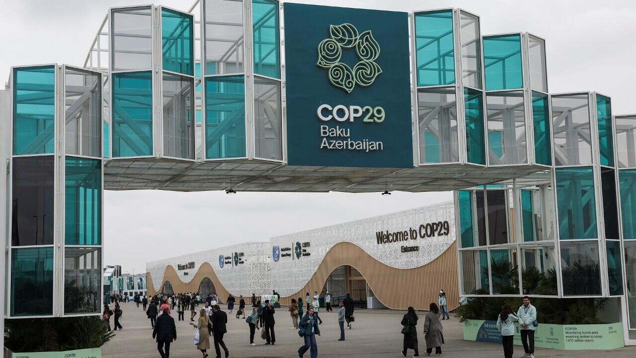 Varias personas caminan a la entrada de la sede de la conferencia de las Naciones Unidas sobre el cambio climático COP29, en Bakú, Azerbaiyán, el 11 de noviembre de 2024.