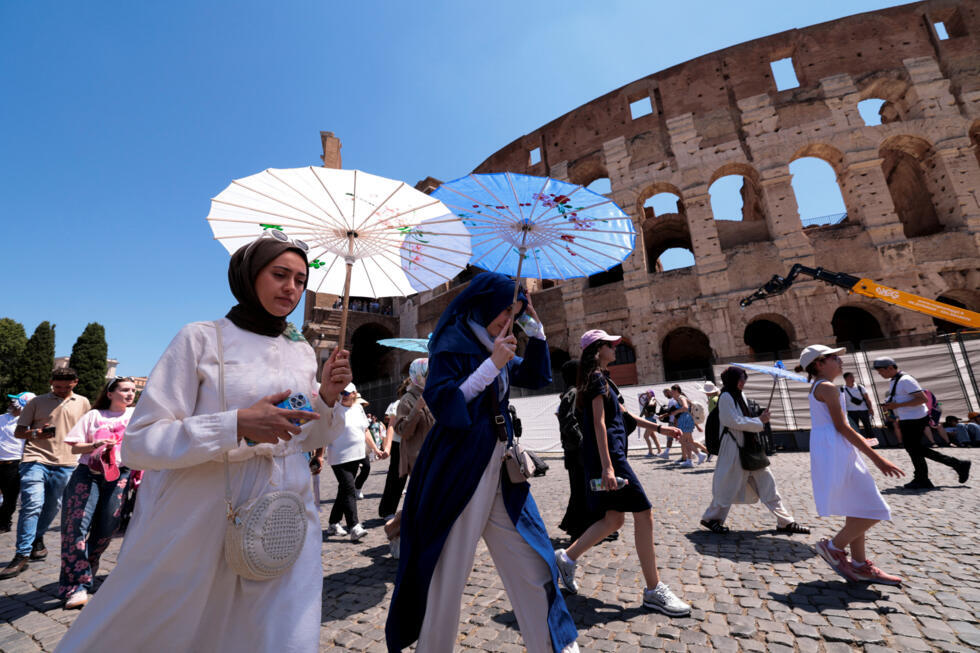 Turistas caminan bajo sombrillas mientras visitan el Coliseo durante una ola de calor veraniega en Roma, Italia, el 30 de junio de 2025.