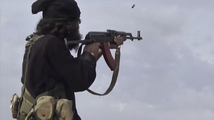 This file frame grab from video posted online March 18, 2019, by the Amaq News Agency, a media arm of the Islamic State group, shows an IS fighter firing his weapon.