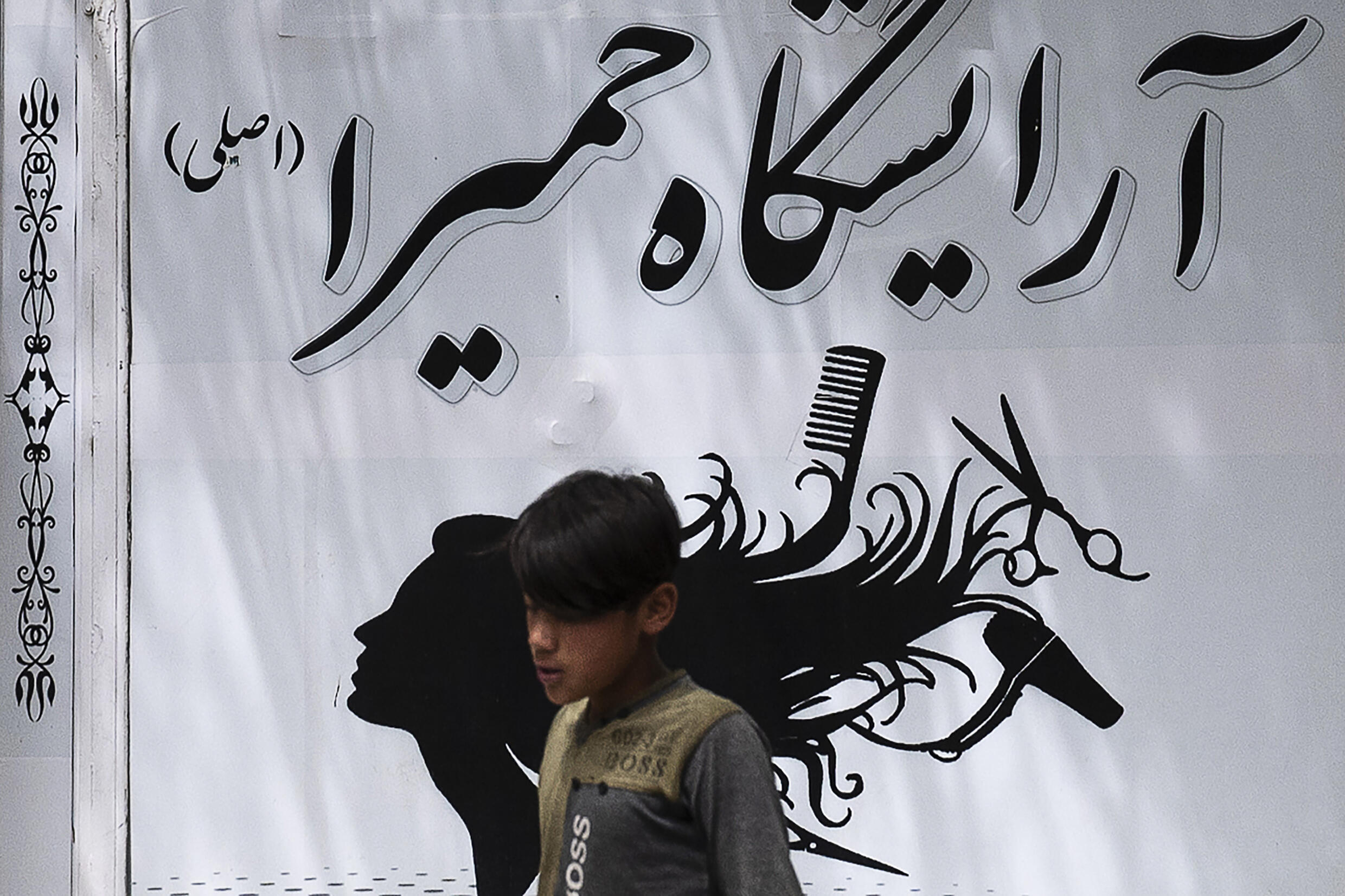 A boy walks past a beauty salon in Kabul