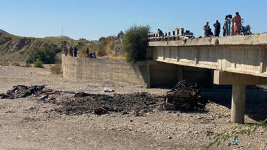 Residents gather over a bridge to watch the wreckage of a burnt passenger bus in the Lasbela district of Pakistan's Balochistan province on January 29, 2023.