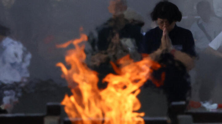People pray in front of the cenotaph for the victims of the 1945 atomic bombing on the 80th Atomic Bombing Day anniversary in Hiroshima, western Japan, August 6, 2025.