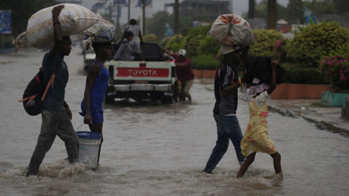 People cross a flooded street during the passage of Tropical Storm Laura, in Port-au-Prince, Haiti August 23, 2020.