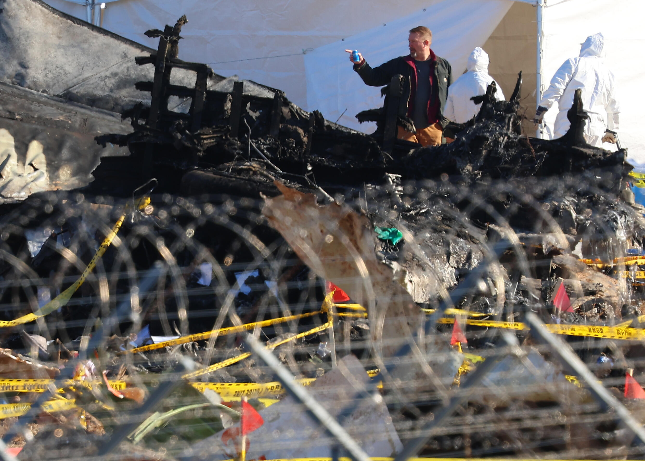 Des enquêteurs de sud-coréens et américains inspectent l'épave du Boeing 737-800 de la Jeju air qui s'est écrasé sur l'aéroport de Muan en Corée du Sud, le 3 janvier 2025