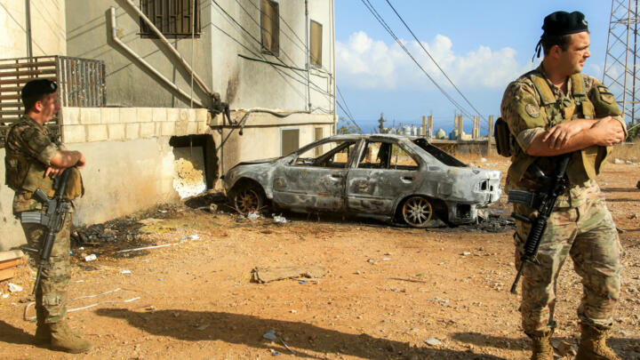 Fighters stand in front of the charred remains of a car in Lebanon, November, 2025. 