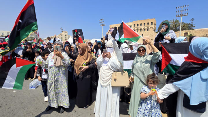 Libyans wave flags as they greet activists heading towards Gaza by land with the aim of breaking the siege on the Palestinian territory, in Tripoli's Martyrs Square on June 11, 2025, one day after cro