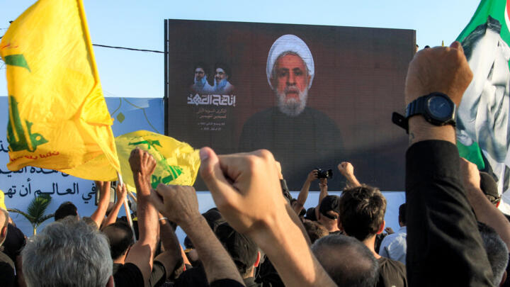 الأمين العام لحزب الله الشيخ نعيم قاسم أثناء خطاب عبر الشاشة في مشهد من بلدة دير قانون النهر في جنوب لبنان بتاريخ 27 أيلول/سبتمبر 2025. 