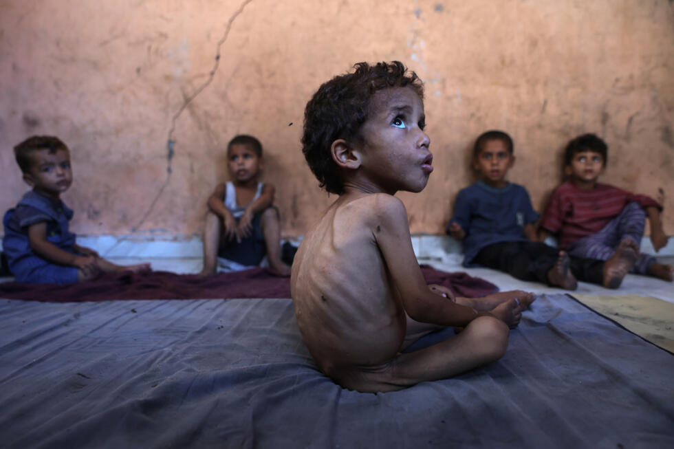 Yazan, un garçon palestinien de 2 ans souffrant de malnutrition, est assis avec ses frères dans la maison endommagée de leur famille dans le camp de réfugiés d'Al-Chati, dans le nord de Gaza, le 23 juillet 2025