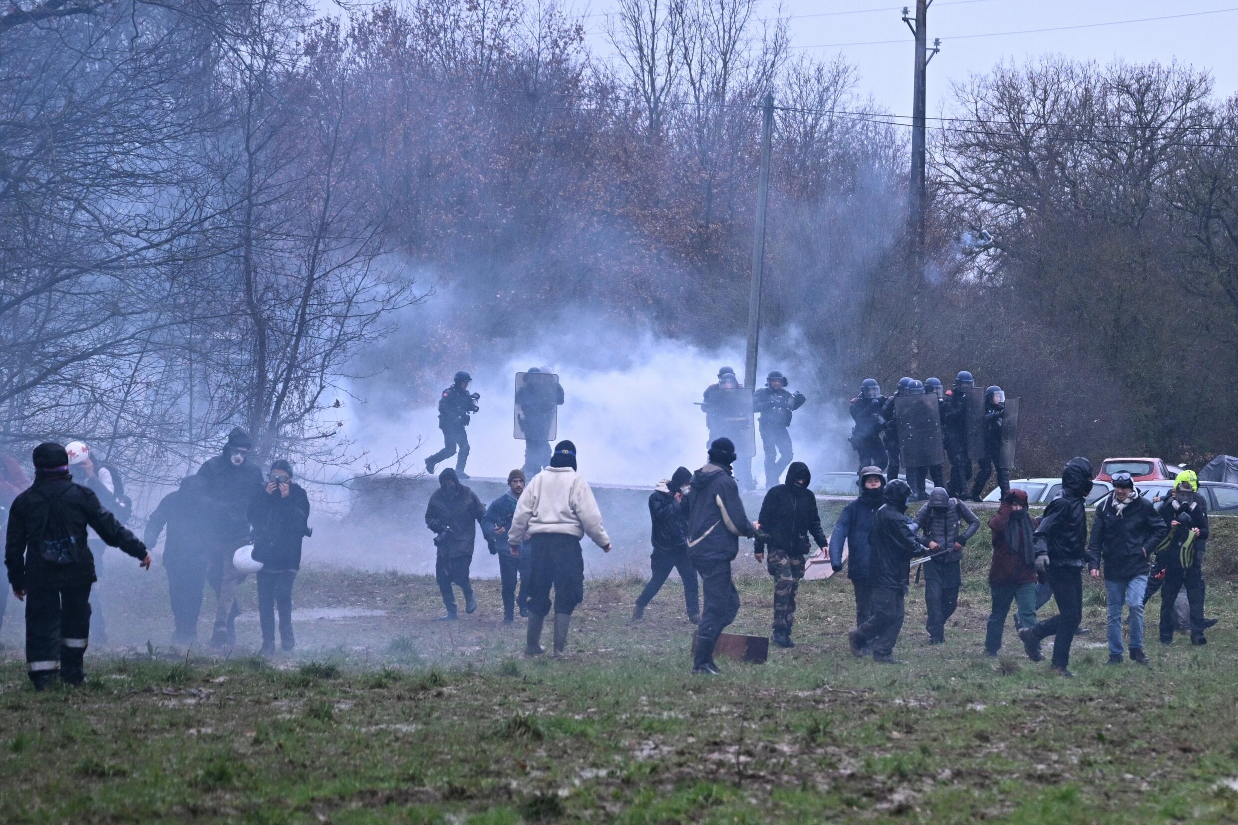 Des opposants à la construction de l'autoroute A69 font face aux gendarmes dans la fumée des gaz lacrymogènes, le 10 février 2024 à Saïx, dans le Tarn.
