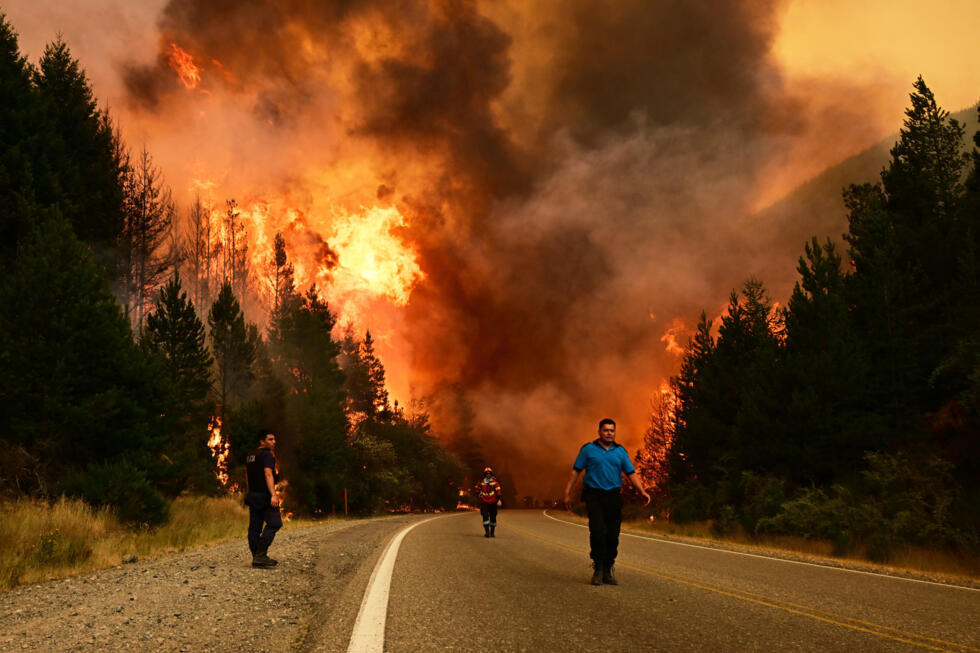 Mensen lopen op een weg terwijl er op 8 januari 2026 een bosbrand woedt in El Hoyo, in de zuidelijke regio Patagonië van Argentinië.