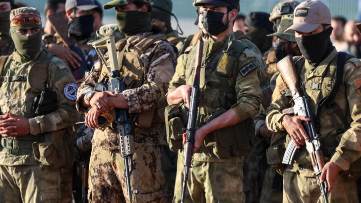 Military fighters affiliated with fHayat Tahrir al-Sham (HTS), attend  prayers at an open air stadium on the first day of the Muslim Eid al-Adha holiday, in Idlib on June 16, 2024.