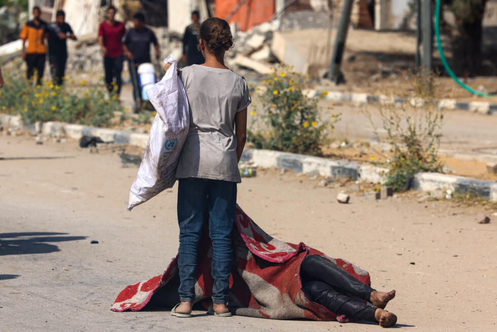 Une enfant palestinienne se tient devant le corps d'une personne tuée en venant chercher des vivres dans un site de distribution de la Fondation humanitaire de Gaza (GHF) soutenue par Israël et les Ét