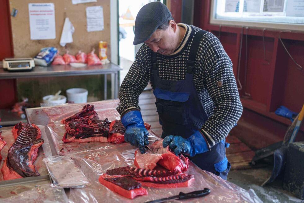 Un homme découpe de la viande de phoque au marché de Nuuk, au Groenland, le 14 janvier 2026