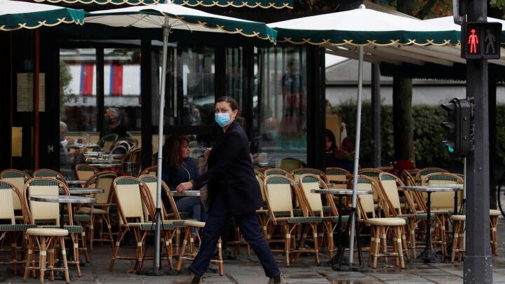 A woman wearing a protective face mask walks past Les Deux Magots cafe in Paris on October 5, 2020.