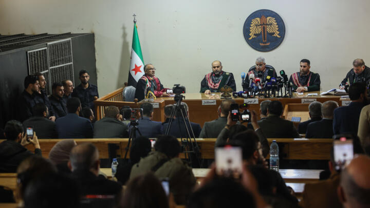 Suspects stand inside a holding cell, left, as judges preside over Syria's first public trial related to deadly clashes in March along the country's coastal provinces, at the Palace of Justice in Alep