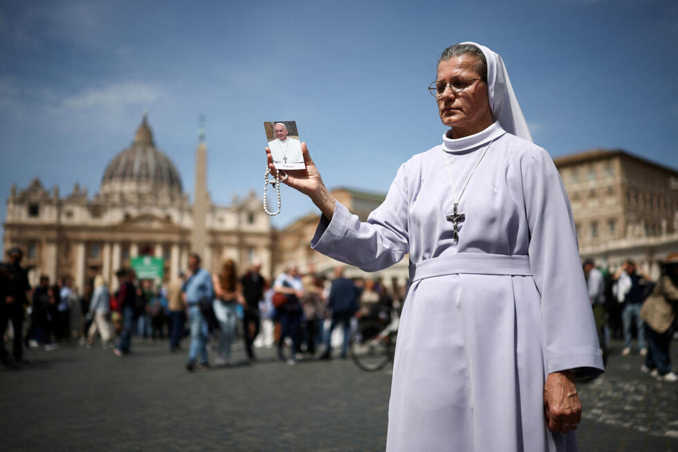 Une religieuse tient une image du pape François près de la place Saint-Pierre, après l'annonce du décès du pape François par le Vatican, le 21 avril 2025