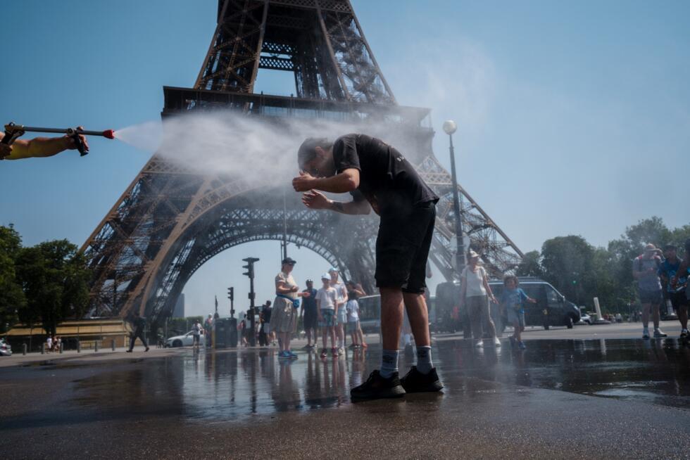Un empleado municipal rocía agua para refrescar a los turistas frente a la Torre Eiffel en París, el 2 de julio de 2025, mientras una ola de calor azota Francia.