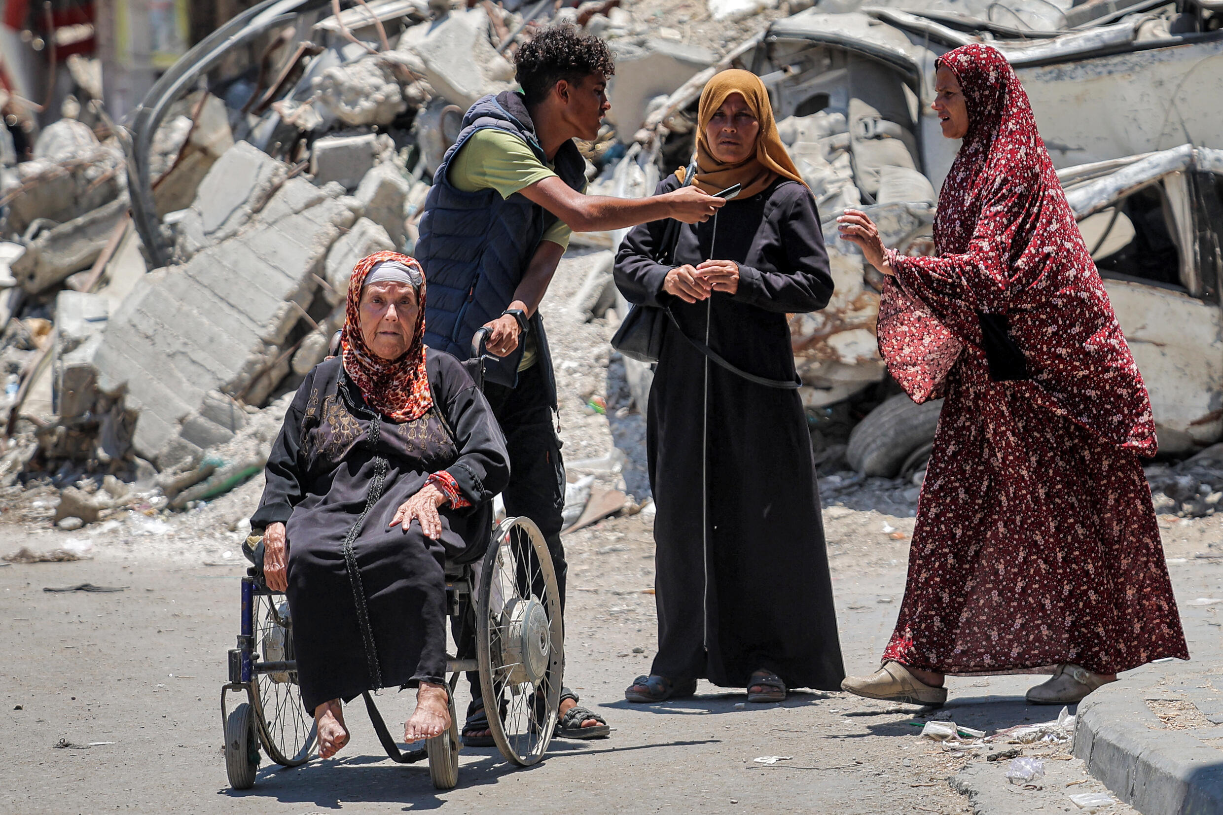 Un Palestinien pousse une femme âgée dans un fauteuil roulant pour évacuer le quartier de Choujaïya dans l'est de la ville de Gaza, le 27 juin 2024