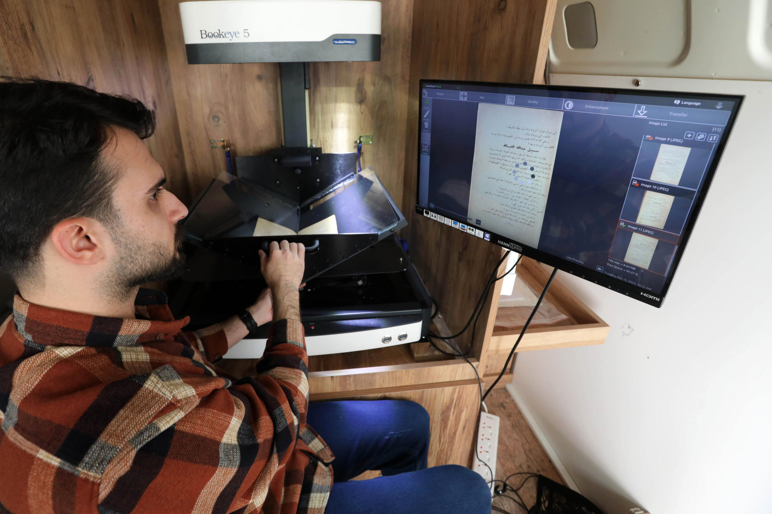 عضو في مركز كردستان للفنون والثقافة يصوّر صفحات كتاب قديم في إطار مهمة لحفظ التراث الكردي المكتوب في دهوك في إقليم كردستان في شمال العراق في 13 شباط/فبراير 2024