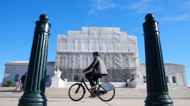 As a person on a bicycle rides past, construction on the front of the U.S. Supreme Court continues Monday, Nov. 24, 2025, in Washington.