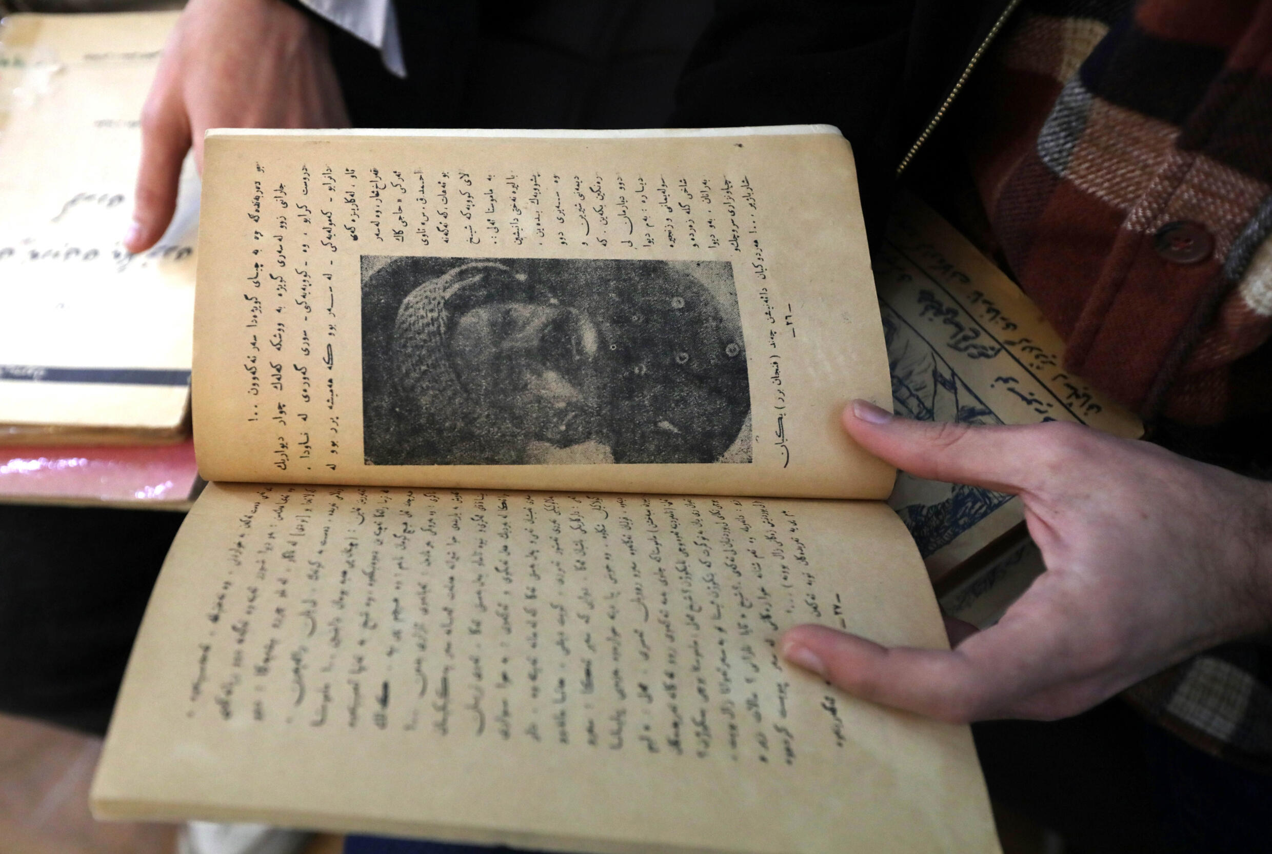عنصر في مركز كردستان للفنون والثقافة يتفحص كتابا قديما تمهيدا لحفظه رقميا في مكتبة دهوك في اقليم كردستان في شمال العراق في 13 شباط/فبراير 2024