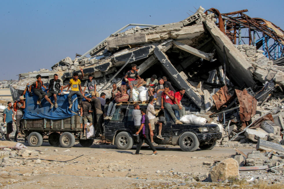 Des personnes voyagent à bord d'un véhicule chargé de sacs d'aide humanitaire reçus dans un centre de distribution géré par la Gaza Humanitarian Foundation (GHF), dans le centre de la bande de Gaza, le 22 août 2025.