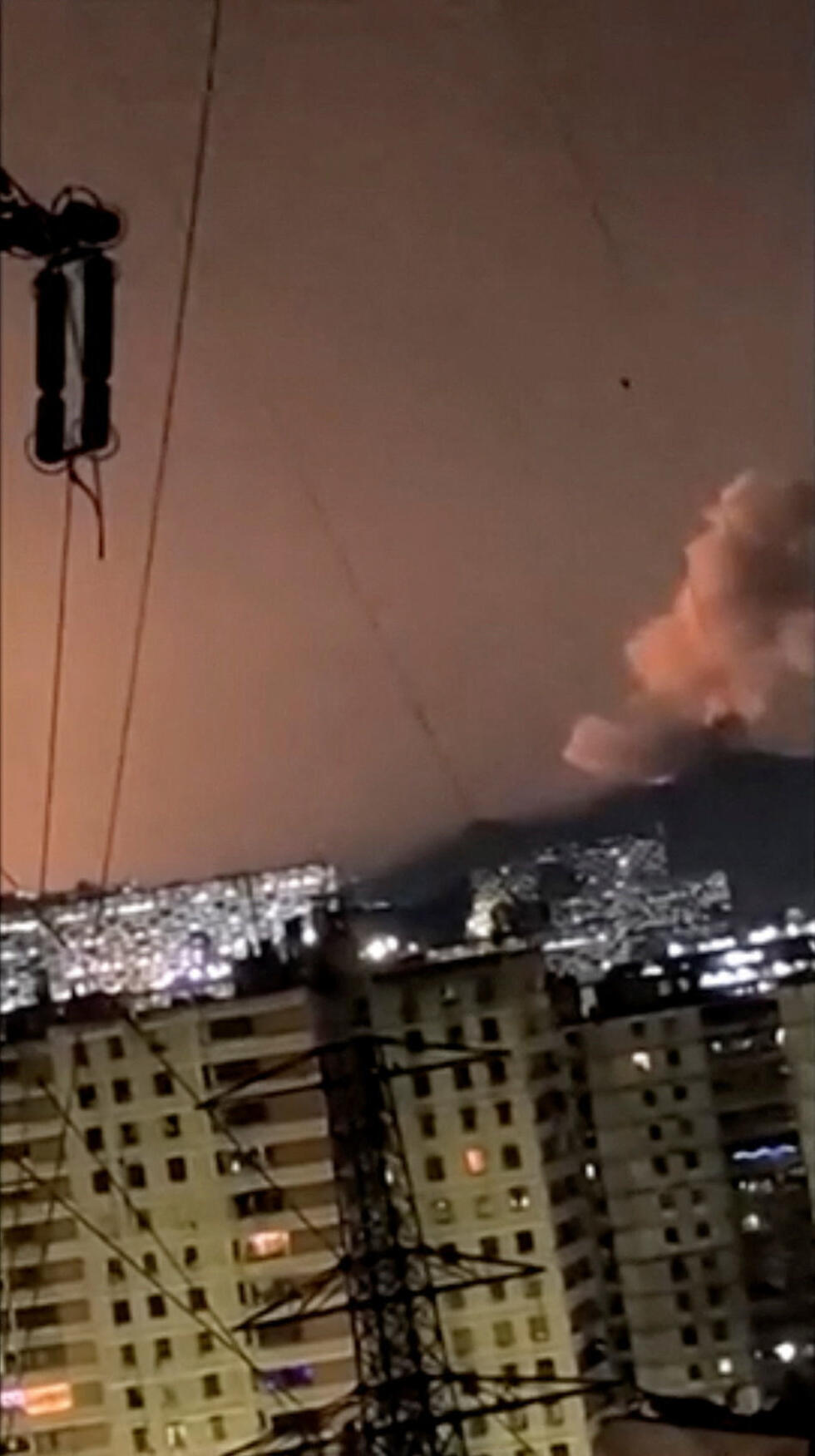 A column of smoke rises following an explosion, as the sky is illuminated by another explosion in the distance in the early hours of the morning, in Caracas, Venezuela, January 3, 2026
