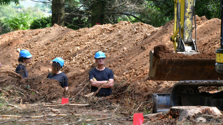 Workers watch as an excavator removes soil during an attempt to exhume the remains of German WWII soldiers executed by French resistance fighters on August 16, 2023.