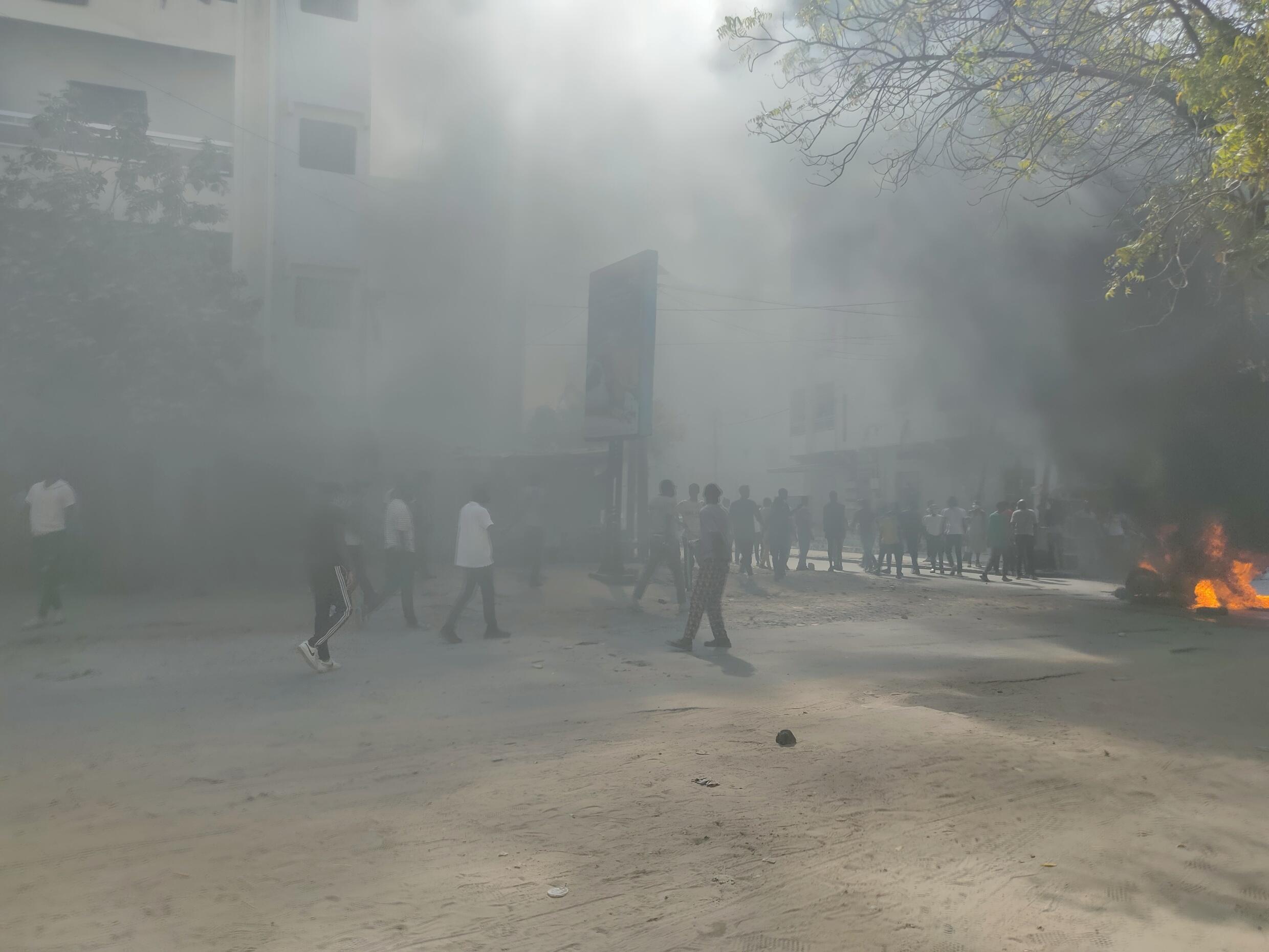 Des fumée noires envahissent une rue derrière une mosquée de Dakar.