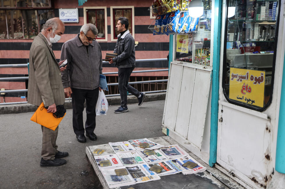 Men look at Iranian daily newspapers reporting on the first round of talks between Iran and the United States at a kiosk in Tehran.