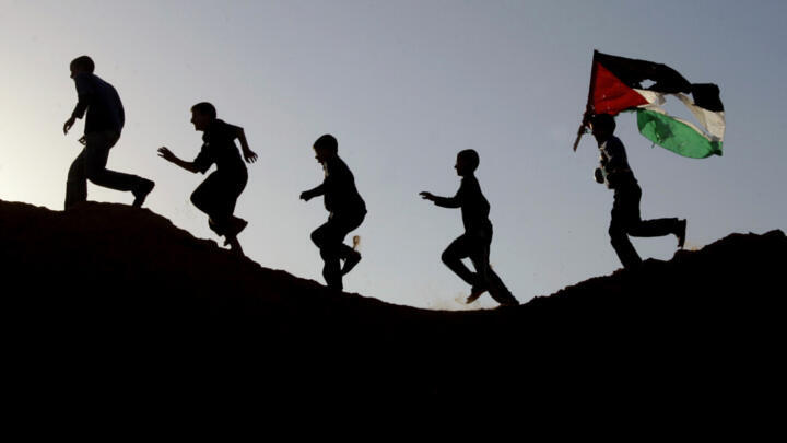 Young Palestinians carry a Palestinian flag through Beit Lahiya in the northern Gaza Strip on 26 November, 2006.