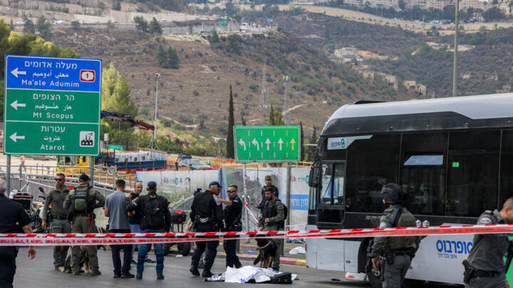 Israeli security forces gather by a body next to a bus at the Ramot road junction in Israeli-annexed east Jerusalem on September 8, 2025.