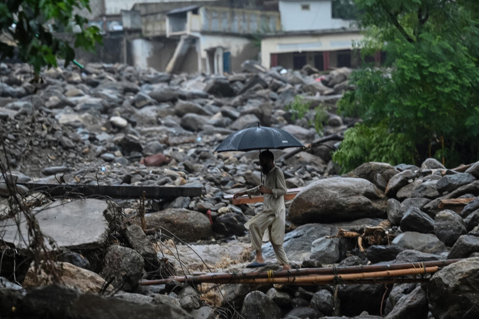 Un villageois traverse un pont de fortune sur le site d'une crue soudaine dans le district de Buner, dans la province de Khyber Pakhtunkhwa, le 18 août 2025 au Pakistan