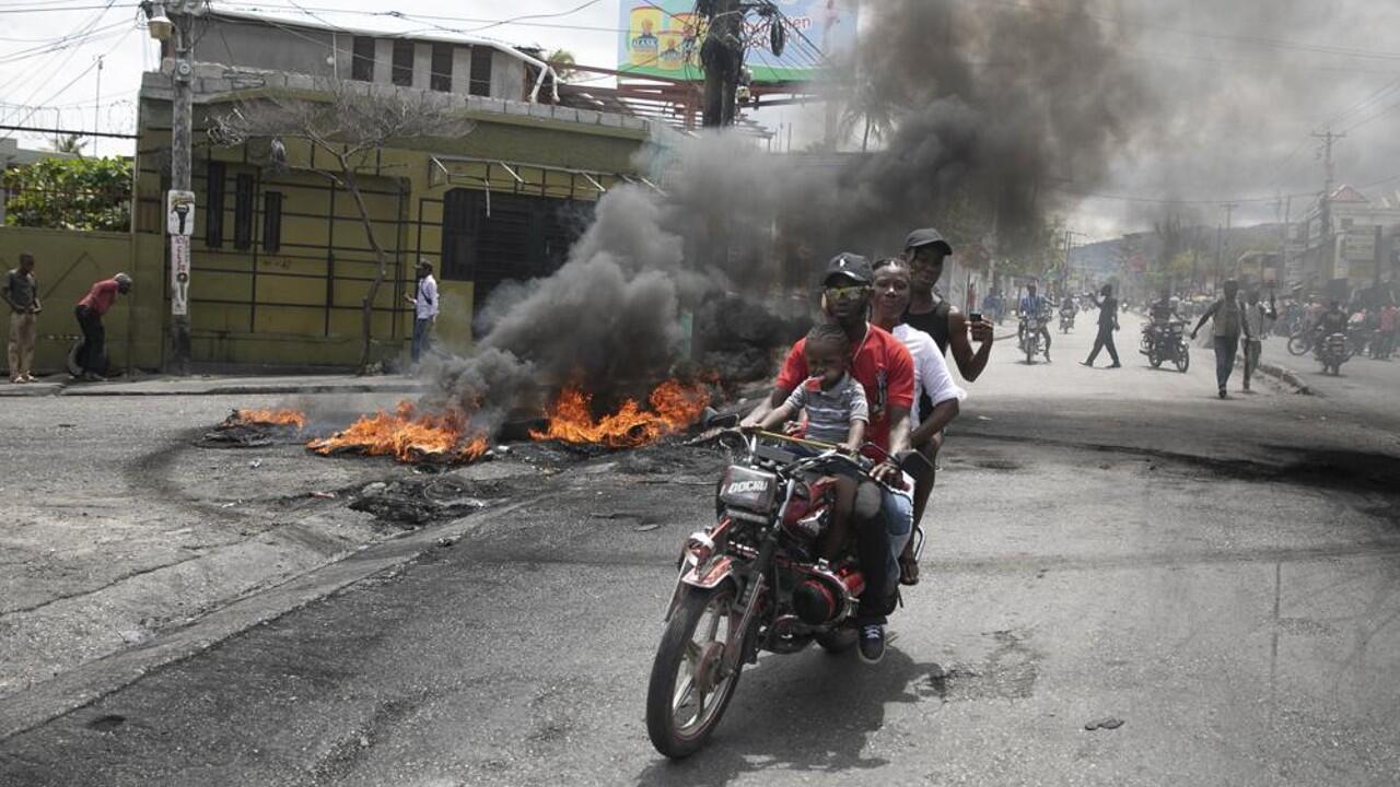 Archivo-Un taxista en motocicleta traslada a clientes cerca de una protesta contra la creciente violencia, el martes 29 de marzo de 2022, en Puerto Príncipe, Haití.