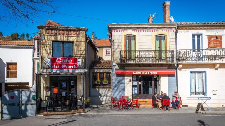 People sit around a table at a bar in the village of Esperaza, near Carcassone in southern France, on February 5, 2020.