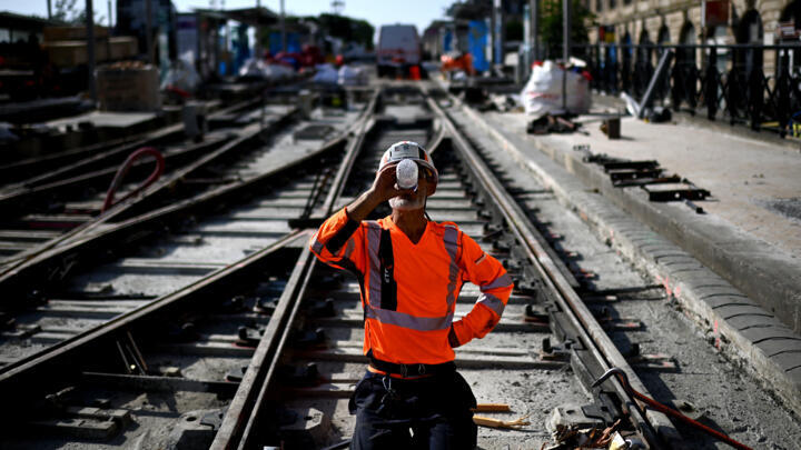 A labourer drinks water to cool down as he works on a construction site of tramway lines along the Garonne river during a heatwave in Bordeaux, south-western France on July 1, 2025. 
