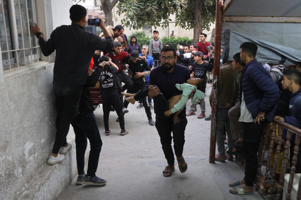 Un Palestinien transporte une fillette blessée à l'hôpital al-Ahli à Gaza-ville, dimanche 6 avril 2025.