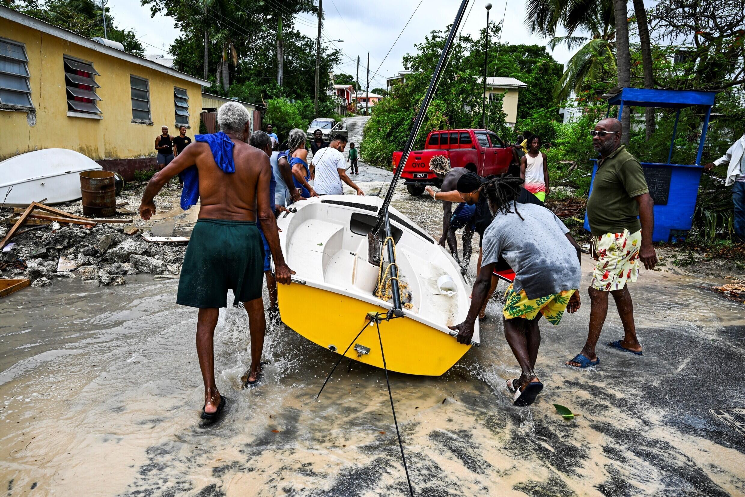 Des habitants dégagent un bateau d'une ruee inondée après le passage de l'ouragan Béryl, près de Bridgetown, le 1er juillet 2024 à la Barbade
