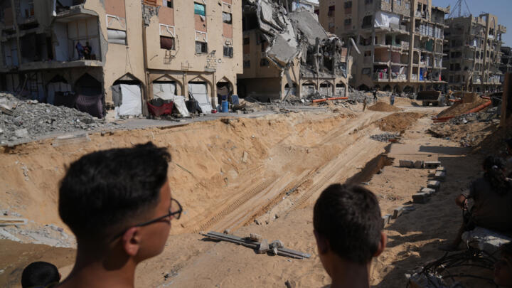 Palestinians watch Hamas members search for bodies in Khan Younis, in southern Gaza on Ocober. 17, 2025.